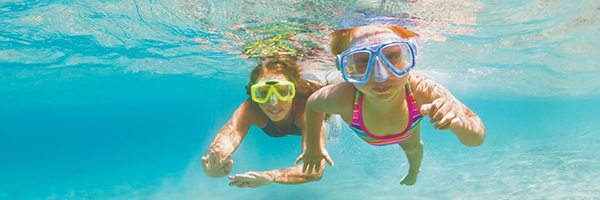 woman and girl swimming underwater with goggles on