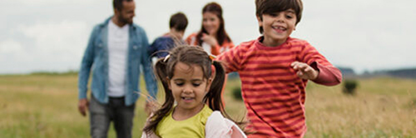 family in a field, kids running in the foreground