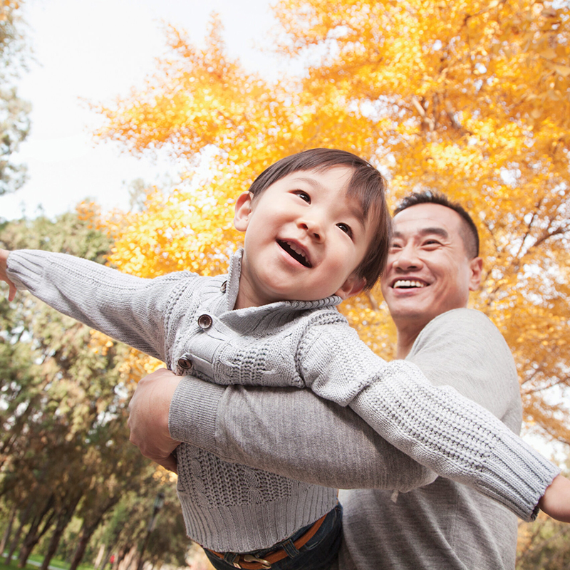 father holding son outdoors in autumn