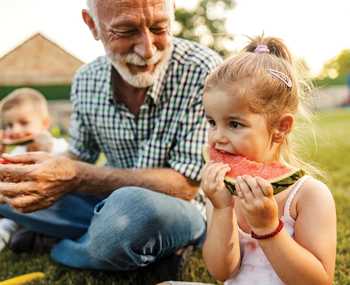 grandfather and granddaughter eating watermelon
