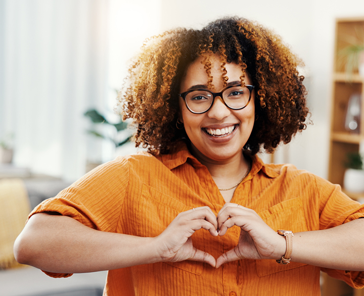 smiling woman making a heart shape with her hands