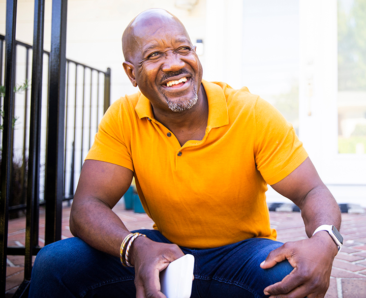 older man sitting on front steps with a coffee mug
