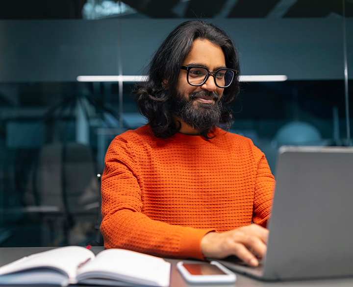 man sitting at a desk working on a laptop