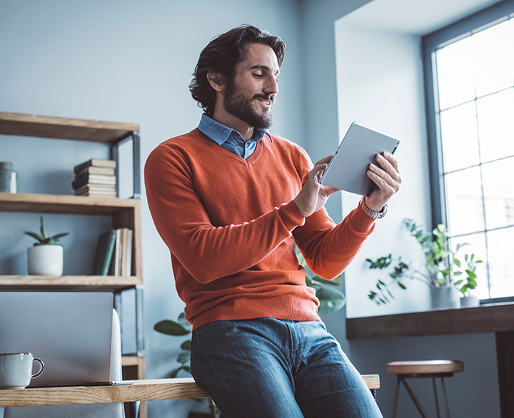 man sitting on a desk looking at a tablet