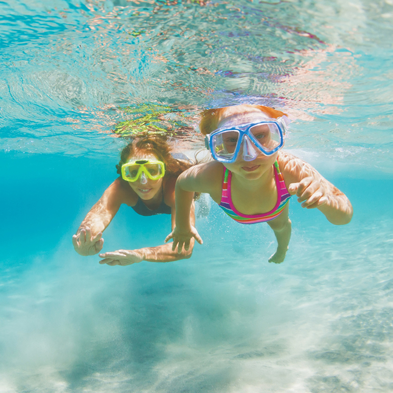 woman and girl swimming underwater with goggles on