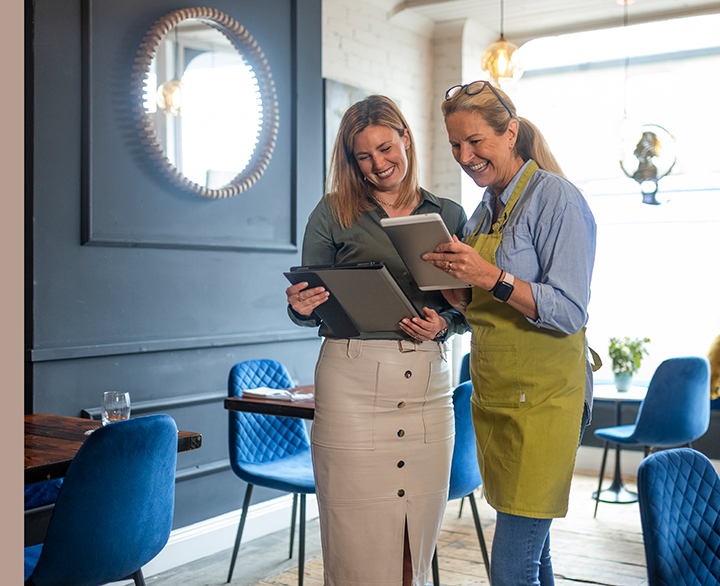 two women in a cafe looking at tablets