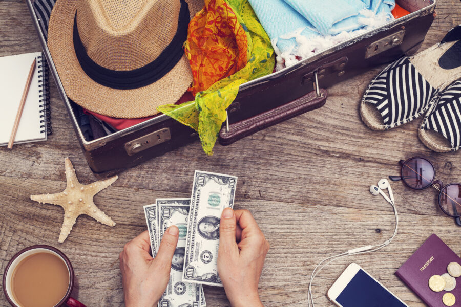 Money saved for summer vacation with suitcase and vacation items.